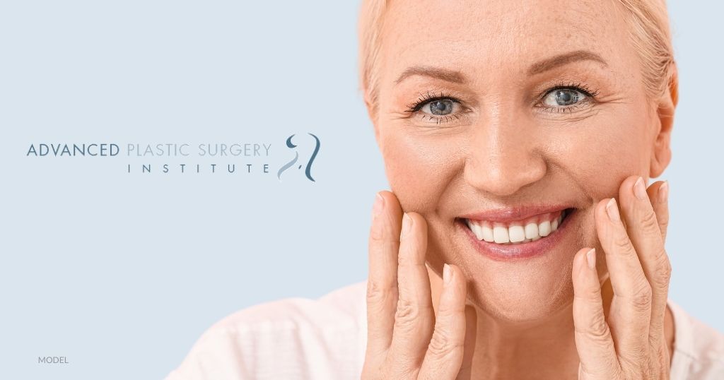 Mature woman smiling and touching her face (model). "Advanced Plastic Surgery Institute" logo.