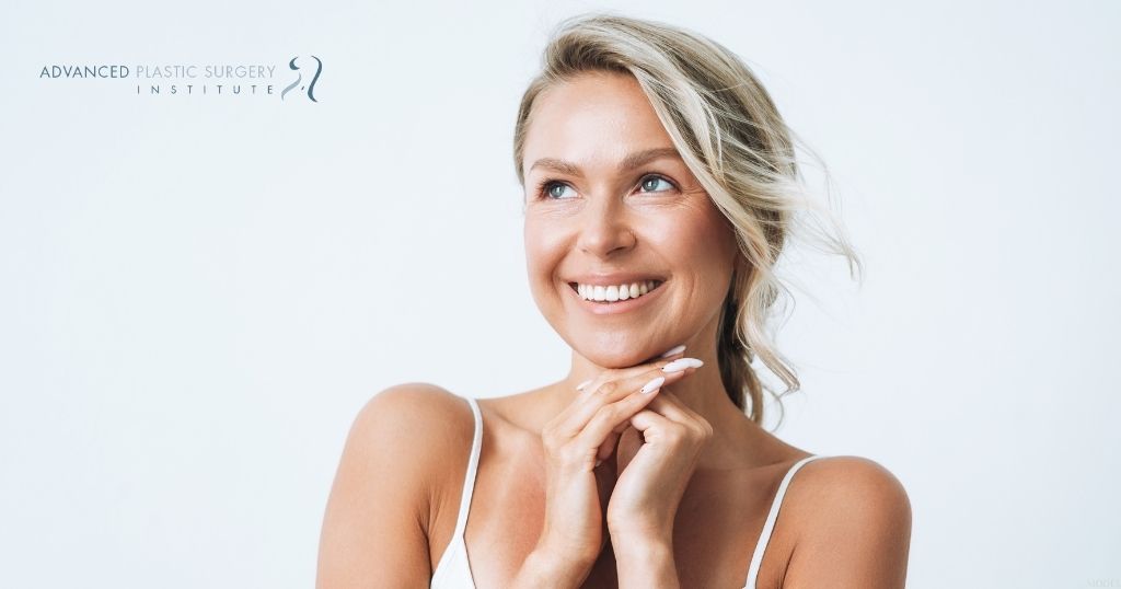 smiling woman posing against a white background (MODEL) Advanced Plastic Surgery Institute Logo